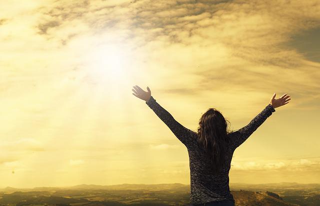 Happy woman spreading arms towards the sun